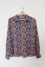 Lataa kuva Galleria-katseluun, Paitapuoserossa on siniselle pohjalla oransseja kuvioita